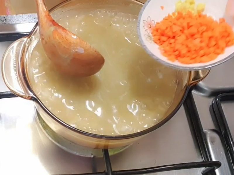 Cho cà rốt vào cháo nấu chín mềm rồi cho bà ngư vào nêm nếm lại gia vị